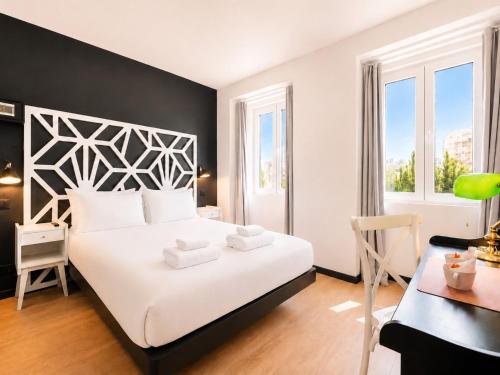a bedroom with a large white bed and a desk at The Twenties by GuestReady in Lisbon