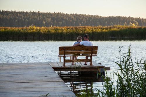 a man and woman sitting on a bench by a lake at Siedlisko Wigry in Rosochaty Róg