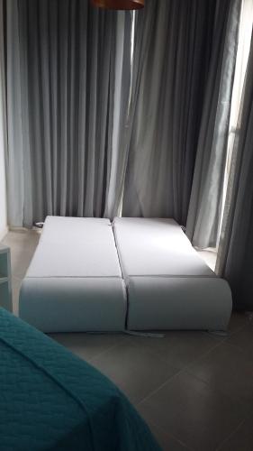 a white bed sitting in a room with a window at Condado Aldeia dos Reis 205 e 213 in Mangaratiba