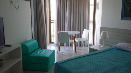 une chambre d'hôtel avec un lit, une table et des chaises dans l'établissement Condado Aldeia dos Reis 114 e 213, à Mangaratiba