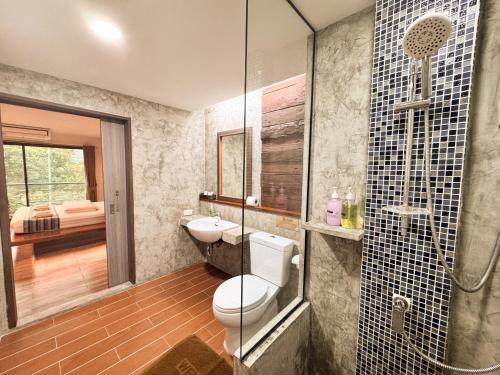 a bathroom with a toilet and a glass shower at Boutique Poo-Yai Lee in Bangkok
