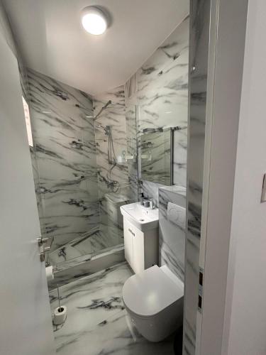 a white bathroom with a toilet and a sink at Beachside Apartments Novalja in Stara Novalja