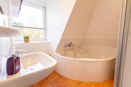 a white bathroom with a tub and a sink at Appartement Tümmelkoje in Sankt Peter-Ording