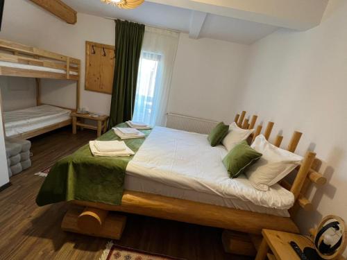 a bedroom with a large bed with green and white pillows at Pensiunea Rancaski in Ranca