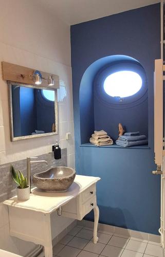 a bathroom with a sink and a blue wall at La Maison du Cèdre in Bénévent-lʼAbbaye