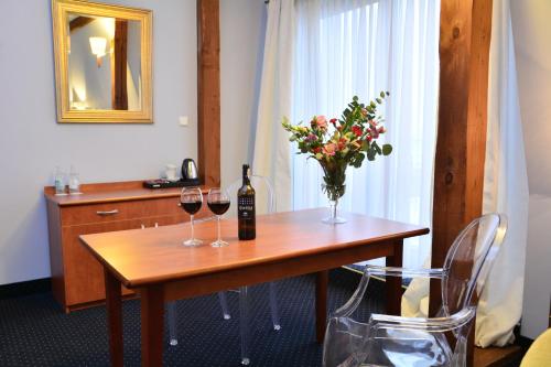 a table with two glasses of wine and a vase of flowers at Rezydencja Solei Strzeszyn in Poznań