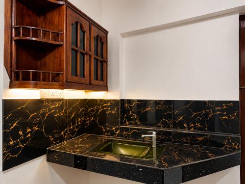 a kitchen with a sink and wooden cabinets at Namali Guest House in Badulla