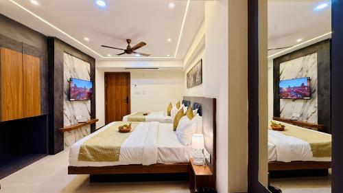 a bedroom with two beds and a ceiling fan at Hotel Aventus Grand in Indore