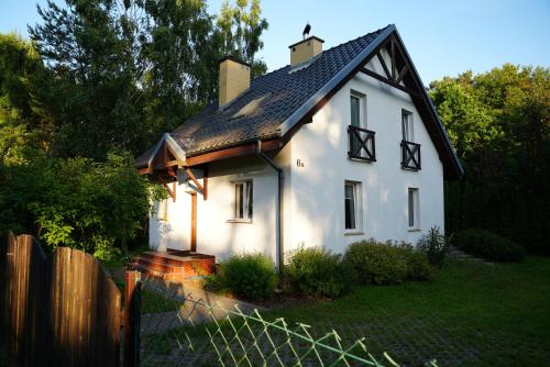 a small white house with a black roof at Domek na Morskiej in Jantar