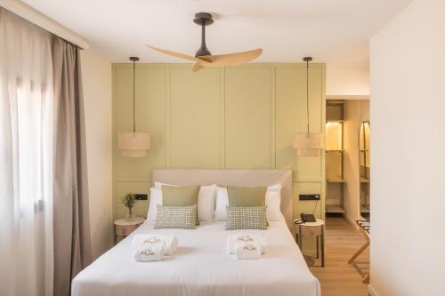 ein Schlafzimmer mit einem weißen Bett und einem Deckenventilator in der Unterkunft The Cookbook Hotel & SPA in Calpe