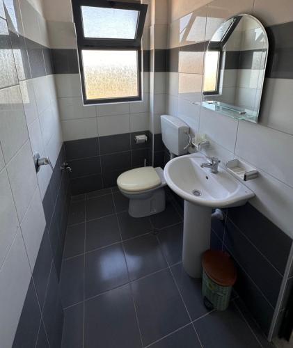 a bathroom with a toilet and a sink and a mirror at Sar Hotel, Velipojë in Velipojë