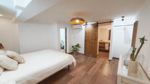 a bedroom with a white bed and a bathroom at Vila Vale Guest House - Surf & Yoga in Charneca