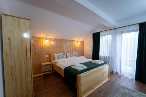 a bedroom with a bed and a large window at Belvedere Retezat in Cîmpu lui Neag