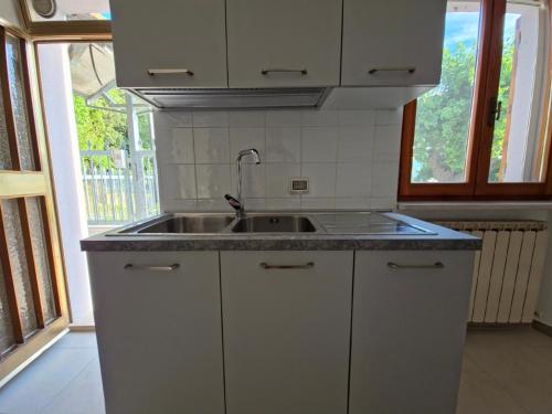 a white kitchen with a sink and a window at Casa Vacanze Merion in Piticchio