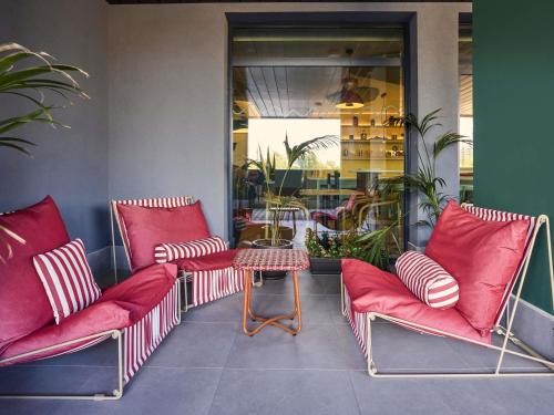 a group of red chairs and a table in a room at Ibis Styles Madrid Airport Valdebebas in Madrid
