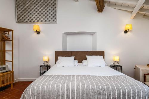 a bedroom with a large bed with two lamps at Quarto Duplo - Pacote Alentejo 3 Noites in Alcáçovas