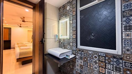 a bathroom with a sink and a mirror on a wall at Hotel Aventus Grand in Indore