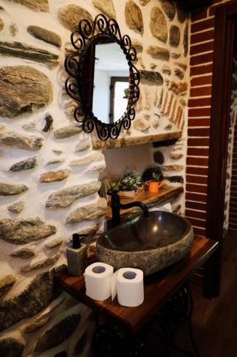 a stone bathroom with a sink and a mirror at Casa de Piatra in Porumbacu de Sus