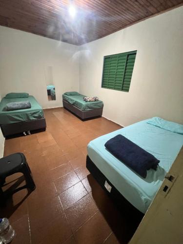 a room with two beds and a chair in it at Casa central in Dourados