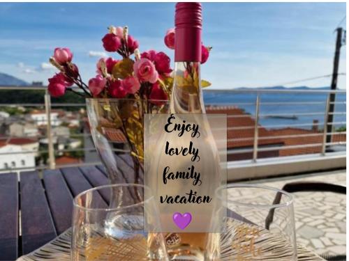 a bottle of wine sitting on a table with flowers at LOVELY APARTMENTS Senj - Spectacular Sea View & Free Parking & WI-FI in Senj