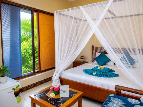 a bedroom with a bed with a mosquito net at Tumaini Bungalows in Nungwi