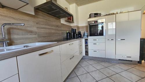 a kitchen with white cabinets and a sink at Auszeit Eifel Ihre private Auszeit zu zweit in Reuth