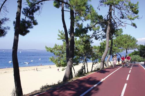 a road next to the beach with people riding bikes at Madame Vacances Les Rives Marines in Le Teich