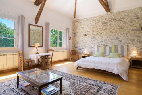a bedroom with a bed and a stone wall at Gite L'Aventura in Régades