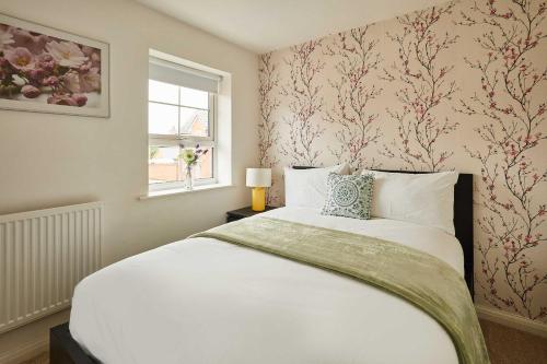 a bedroom with a large white bed with floral wallpaper at Host & Stay - Fells Paddock in Bedford