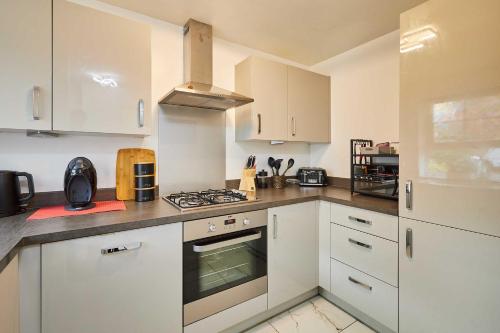a kitchen with white cabinets and a stove top oven at Host & Stay - Fells Paddock in Bedford