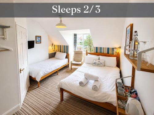 a bedroom with two beds and a chair at Holly Trees Guest Accommodation in Seahouses