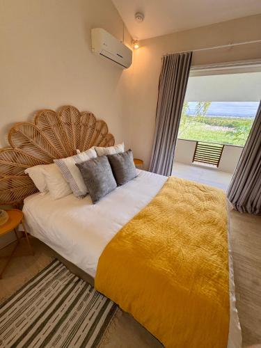 a bedroom with a large bed with a yellow blanket at Villa Kanasuk in Pointe d'Esny