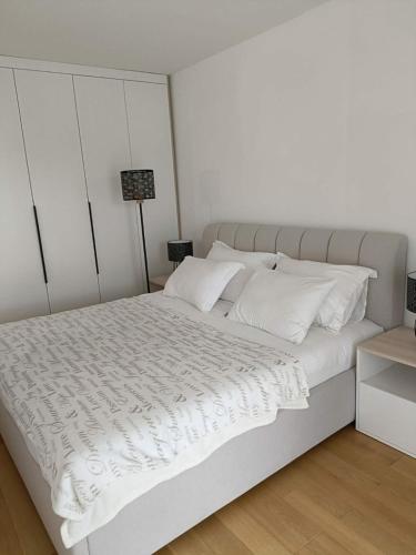 a white bed with white sheets and pillows at Modern Riverside Apartment in Sarajevo