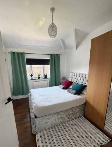 a bedroom with a large bed with green curtains at Piotr House in Warrington