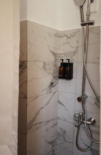 a shower in a bathroom with a white marble wall at Sun Garden House Athens in Nea Makri
