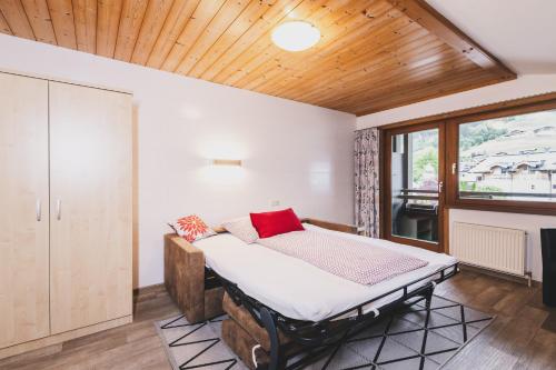 a bed in a room with a wooden ceiling at Haus Voglreiter - inkl Sommerkarte, zentrale und ruhige Lage, Garten mit Spielplatz in Kaprun