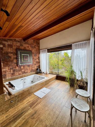 a large bathroom with a tub and a large window at Casa do Teuler - Lapinha da Serra in Santana do Riacho