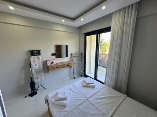 a white bedroom with a bed and a window at Benan Apart Otel Didim in Didim