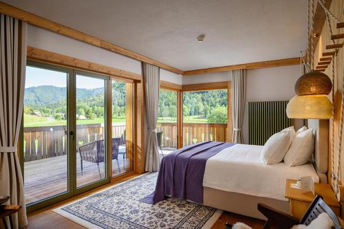 a bedroom with a large bed and a balcony at Vila Planinka Boutique Hotel in Zgornje Jezersko