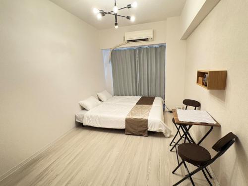 a bedroom with a bed and a table and chairs at Stay min NAKAMURA in Nagoya