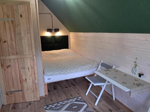 a small room with a bed and a table at Malowane Wrota Camp - Gniazdko in Łazy