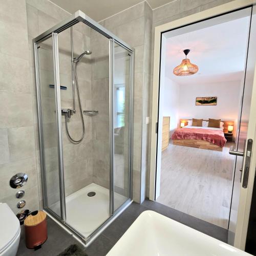 a bathroom with a shower and a toilet and a bed at Studio Premium - Jardin privatif - Parking in Epalinges