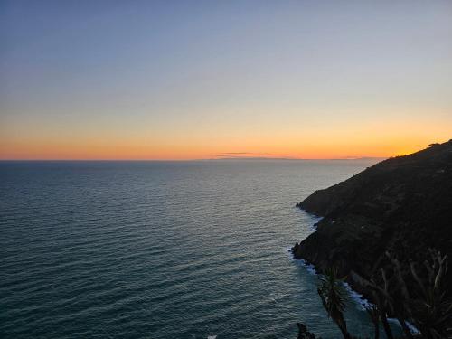 a sunset over the ocean next to a cliff at Il Borgo Di Campi in Riomaggiore