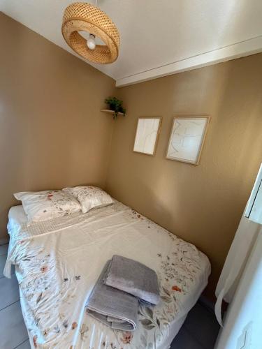 a small bed in a room with a fan at Apartment - Beach - AC - Private parking in Saint-Cyprien-Plage