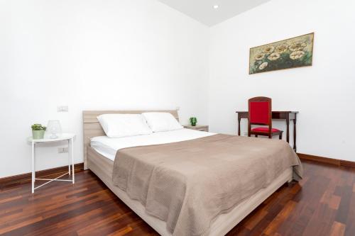 a bedroom with a large bed and a red chair at Tropical House in San Leonardello