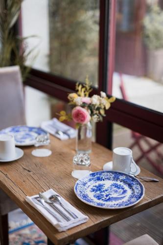 a wooden table with blue and white plates and a vase of flowers at Hôtel Spa - Au Charme Rabelaisien in Amboise