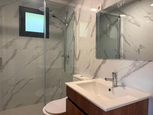 a bathroom with a sink and a glass shower at Outeiro do Moinho - Rooms & Bungalows in Campo do Gerês