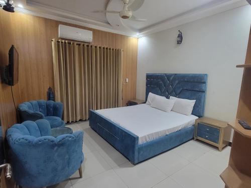 a bedroom with a bed and two blue chairs at INTOWN Hotel in Islamabad