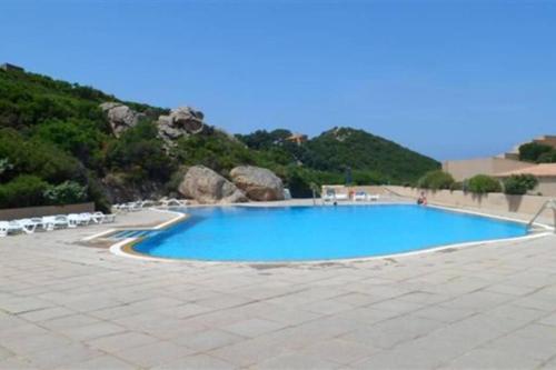 a large blue swimming pool with chairs and a mountain at Appartamento "Hic et Nunc" in Costa Paradiso
