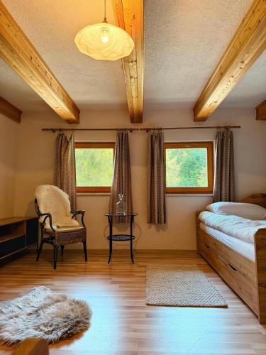 a bedroom with a bed and a chair and windows at Das Försterhaus 41 in Aschau